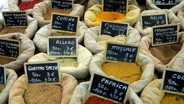 A variety of spices in bags with labels and prices at a market.