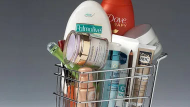Basket filled with various skincare and beauty products, including Palmolive, Dove, and other creams and pencils.