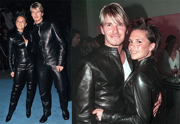 David and Victoria Beckham in matching black leather outfits at an event, smiling and posing on a blue carpet.