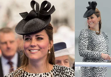 Royal woman in black hat and spotted dress, smiling at an outdoor event.