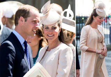 Pregnant woman in cream outfit and hat attends outdoor event, accompanied by a man in a suit.