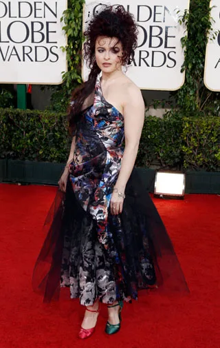 Person in colorful dress with mismatched shoes on a red carpet at the Golden Globe Awards.