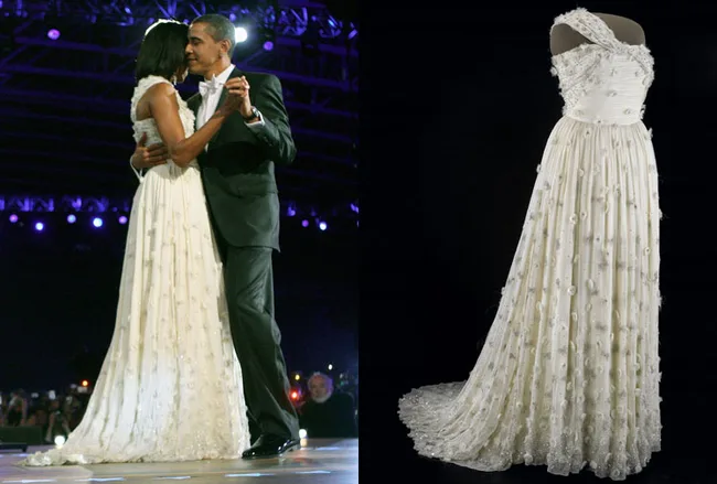 A couple dancing at an inaugural ball; a white one-shoulder gown with floral details displayed on the right.