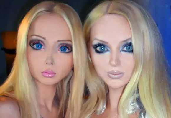 Two women with styled hair and makeup resembling Barbie dolls, featuring large eyes, smooth skin, and glossy lips.