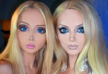Two women with styled hair and makeup resembling Barbie dolls, featuring large eyes, smooth skin, and glossy lips.