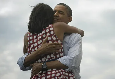 Couple embracing warmly against a cloudy sky backdrop.
