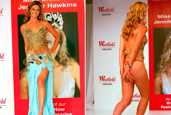 Miss Universe Jennifer Hawkins at a fashion show wearing a gold top and blue skirt, along with a wardrobe slip incident.