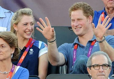 "Prince Harry and a cycling gold medallist smiling while seated at a sports event."