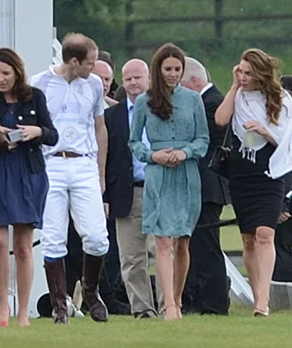 A group of people walking on grass, including a man in a polo outfit and a woman in a green dress.