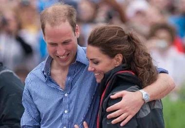 Couple walking closely, smiling together in a crowd.