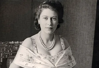 A young woman in a formal gown and pearls, seated, with a calm expression in a classic portrait.