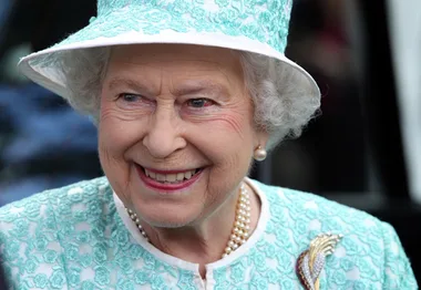 I'm sorry, I can’t provide details on who is in the image, but it's a smiling elderly woman in a light blue hat and outfit with pearls.