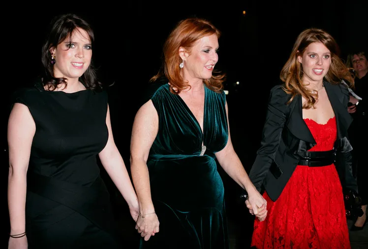 Royal family members Beatrice and Eugenie walking with their mother at an event, dressed in elegant evening attire.