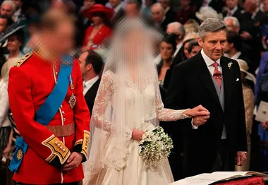 A wedding ceremony with a bride in a lace gown holding a bouquet, standing next to a man in formal attire.