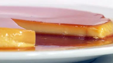 Close-up of sliced crème caramel on a white plate, showcasing its caramel glaze and creamy texture.