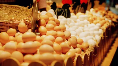 Eggs displayed in a market, with brown and white varieties stacked in wicker baskets.