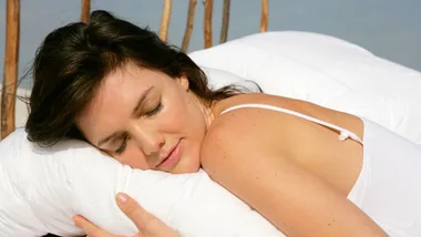 Woman peacefully sleeping on white pillow outdoors.
