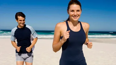 People jogging on a sunny beach, showcasing fitness and outdoor activity.