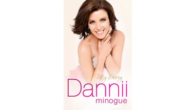 Cover of "My Story" by Dannii Minogue with her smiling, seated and embracing her shoulders against a light background.