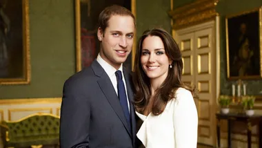 A couple in formal attire stand together in an elegant room with green walls and gold decor.