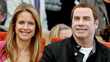 Two smiling individuals sitting closely, with a blurred background.