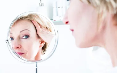 woman looks in mirror