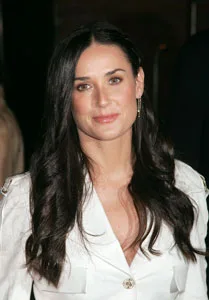A woman with long dark hair in a white top, smiling slightly, with a blurred background.