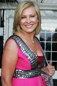 I don't know who this person is. A woman in a pink dress with metallic details smiles outdoors at an event.