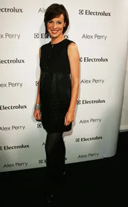 A woman in a black dress poses at an event with Electrolux and Alex Perry branding in the background.