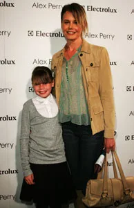 A woman and a young girl smiling at a fashion event, standing in front of a backdrop with "Alex Perry" and "Electrolux" logos.