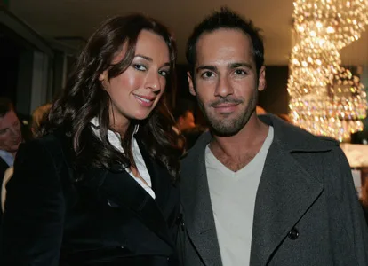 Two people smiling at a formal event with a chandelier in the background.