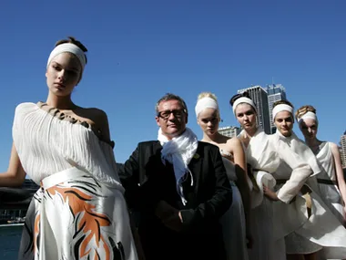 Group of models in white outfits with a designer, posing outdoors during Australian fashion week.
