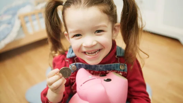 Little girl with coin and piggy bank