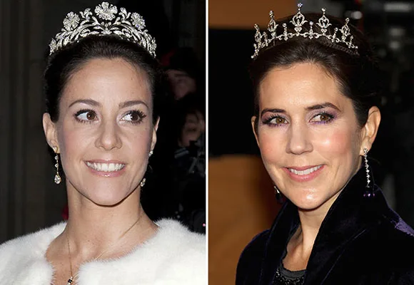 Women wearing tiaras, smiling at an event, dressed in formal attire.