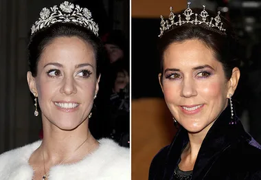 Women wearing tiaras, smiling at an event, dressed in formal attire.