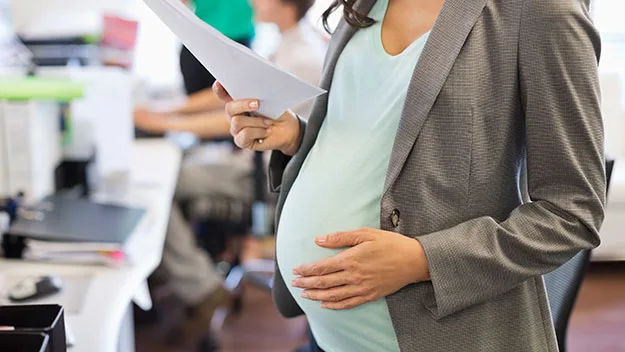 Pregnant woman at work touching stomach