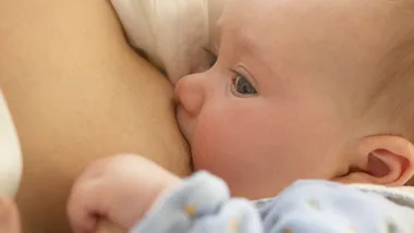 A baby nursing at a mother's breast, close-up.