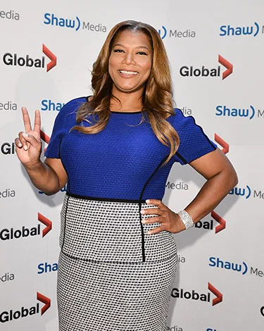 Woman in blue dress poses with a peace sign at a Shaw Media event backdrop.