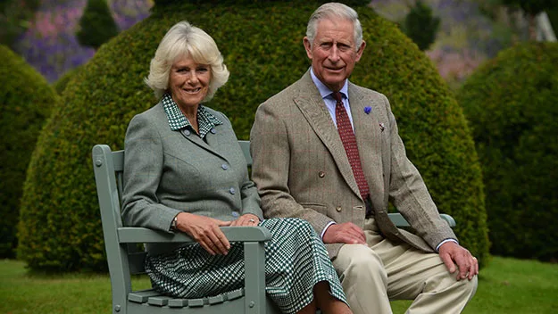 Couple seated on a bench in a garden, with greenery and flowers in the background.