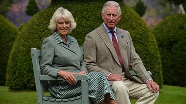 Couple seated on a bench in a garden, with greenery and flowers in the background.