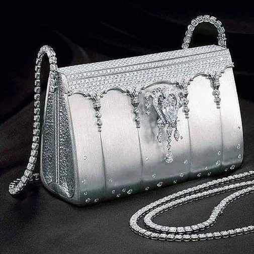 Luxurious silver handbag adorned with sparkling diamonds and elegant details, placed on a dark surface.
