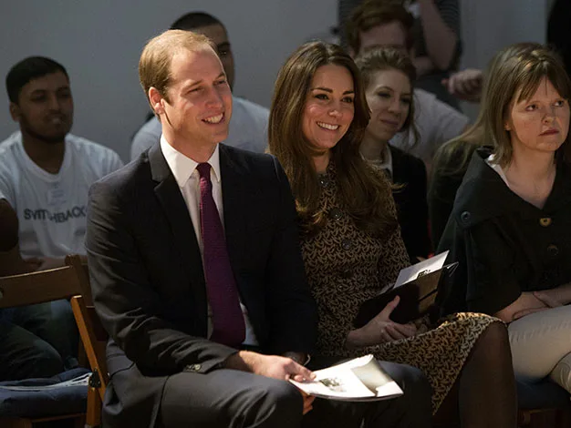 Individuals sitting in an audience, smiling and attentively watching an event or presentation.