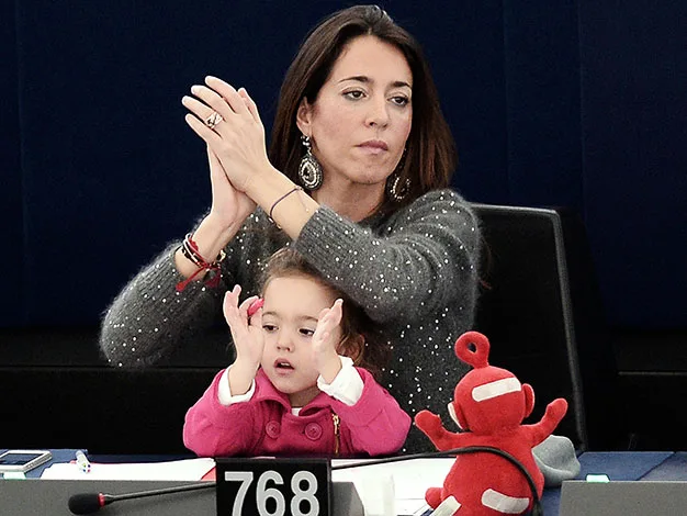 Woman clapping with a child in pink sitting at a desk, red toy in front, number 768 displayed.