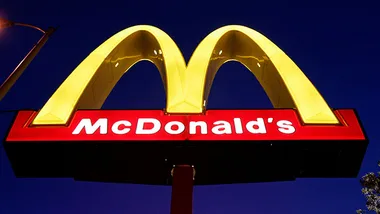 McDonald's sign with glowing yellow arches at night against a deep blue sky.