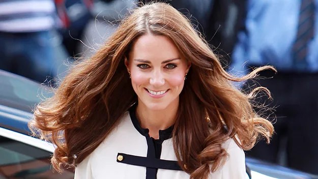 "Smiling woman with long brown hair, wearing a white blouse with black accents."