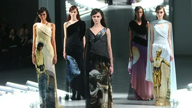 Models walking in gowns featuring Star Wars characters like Yoda, C-3PO, and a galaxy theme on a fashion runway.