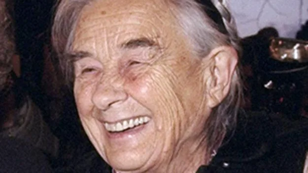 An elderly woman with gray hair smiling warmly.