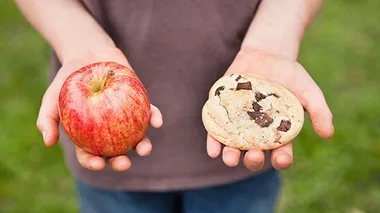 Photo: Michael Hevesy via Getty Images apple and cookie in each hand