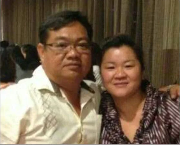 A man and a woman smiling and posing together indoors, with curtains in the background.
