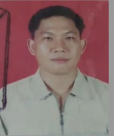Portrait of a man with short dark hair, wearing a light-colored shirt, against a red background.
